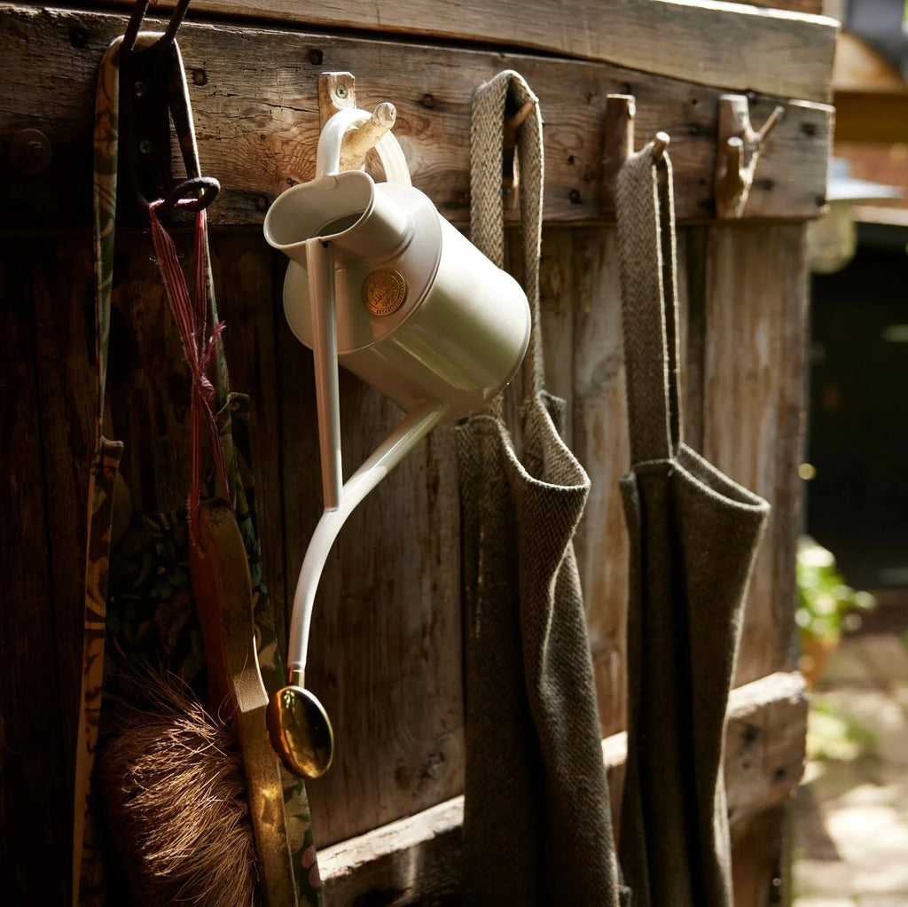 Haws Gardening tools hanging on a wooden wall with a garden in the background