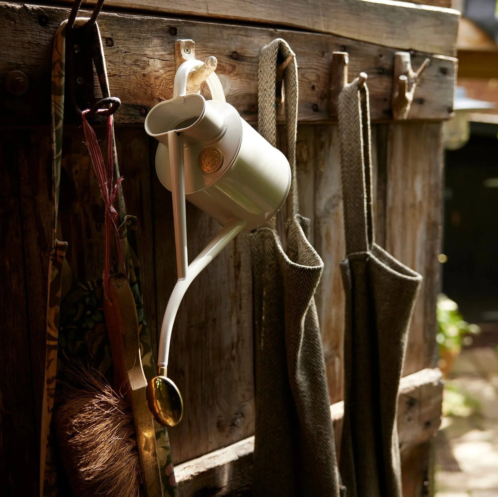 Haws Gardening tools hanging on a wooden wall with a garden in the background